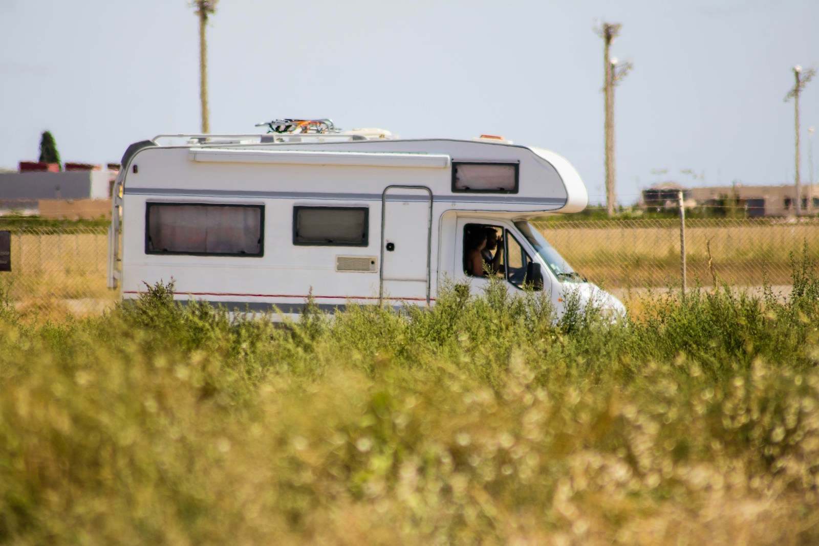 white and brown rv with rv insurance on green grass field during daytime