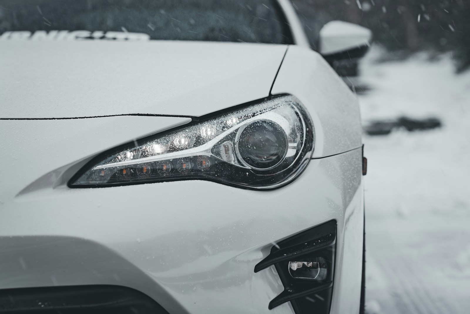 A white car driving down a snow covered road
